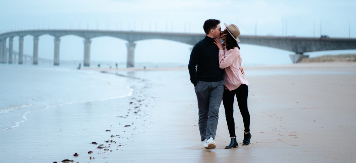 couple s'embrassant sur la plage devant le pont de l'ile de ré, photo en couleur