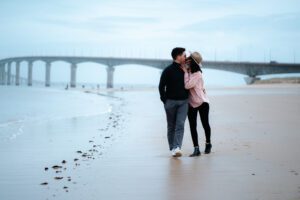 shooting photo de couple s'embrassant sur la plage devant le pont de l'ile de ré, photo en couleur