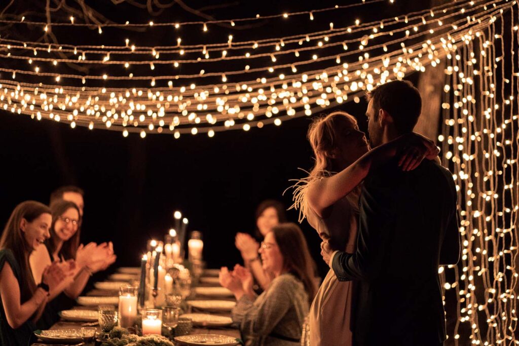 couple s'enlace sous ciel de lumieres, scene de nuit. les invités applaudissent