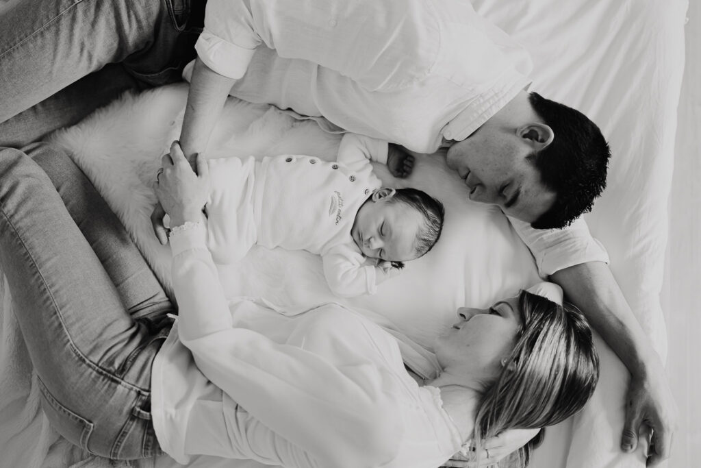 seance photo famille avec nouveau-né, allongés sur lit blanc, photo en noir et blanc