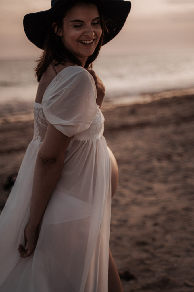 portrait de femme enceinte, robe blanche et chapeau, elle rie sur la plage, ile de ré