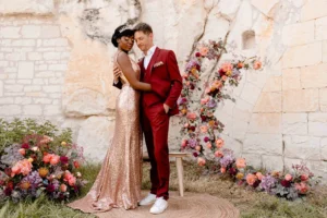 photographe de mariage à la rochelle. Couple en tenues roses devant leur arche de ceremonie laïque fleurie