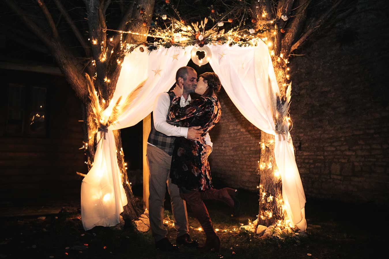 couple s'embrasse sous une arche lumineuse, scene nocturne