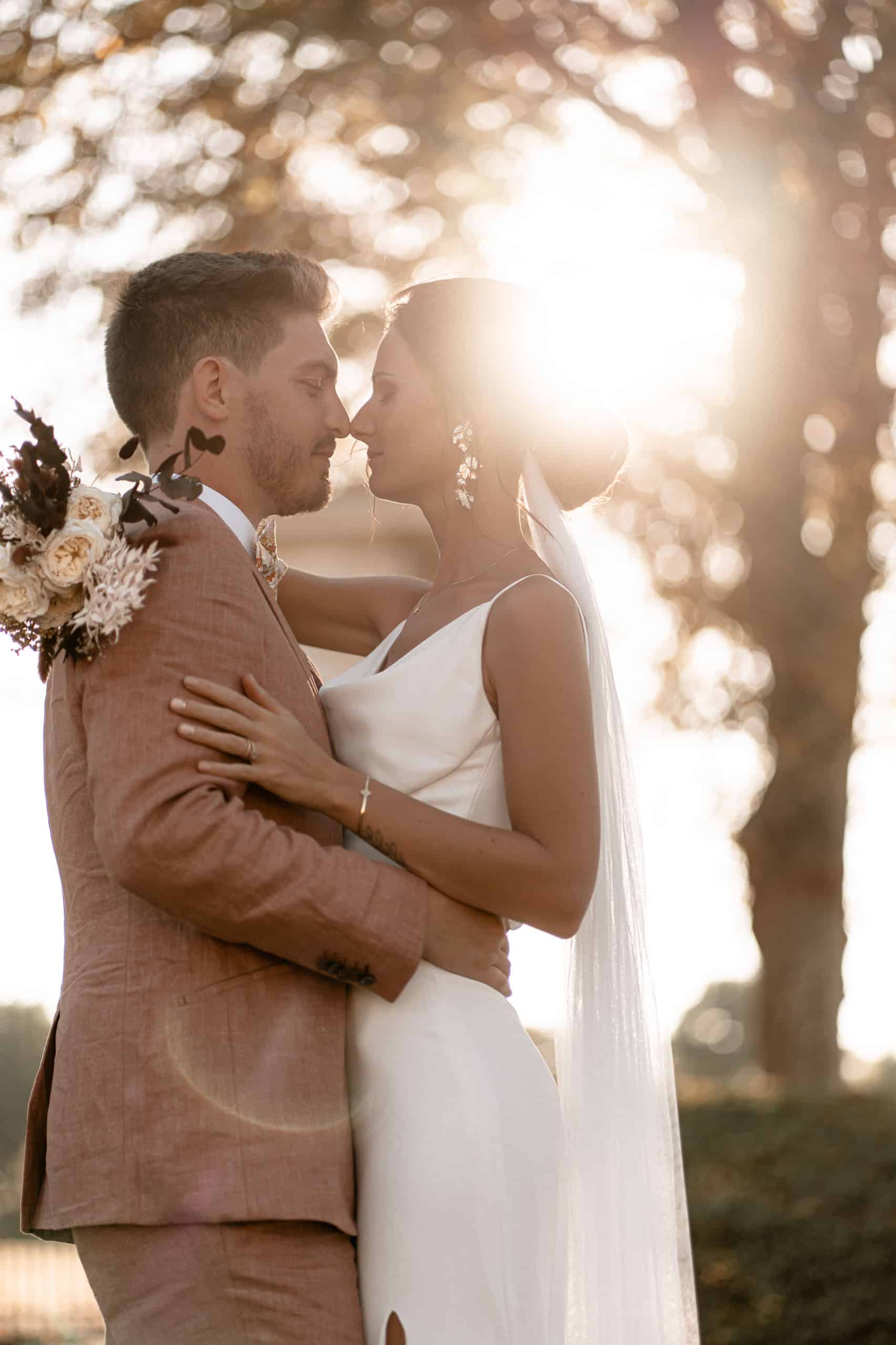 Homme et femme s'embrassant au coucher du soleil sous les arbres. séance couple mariage à la rochelle, abbaye de la grace dieu.