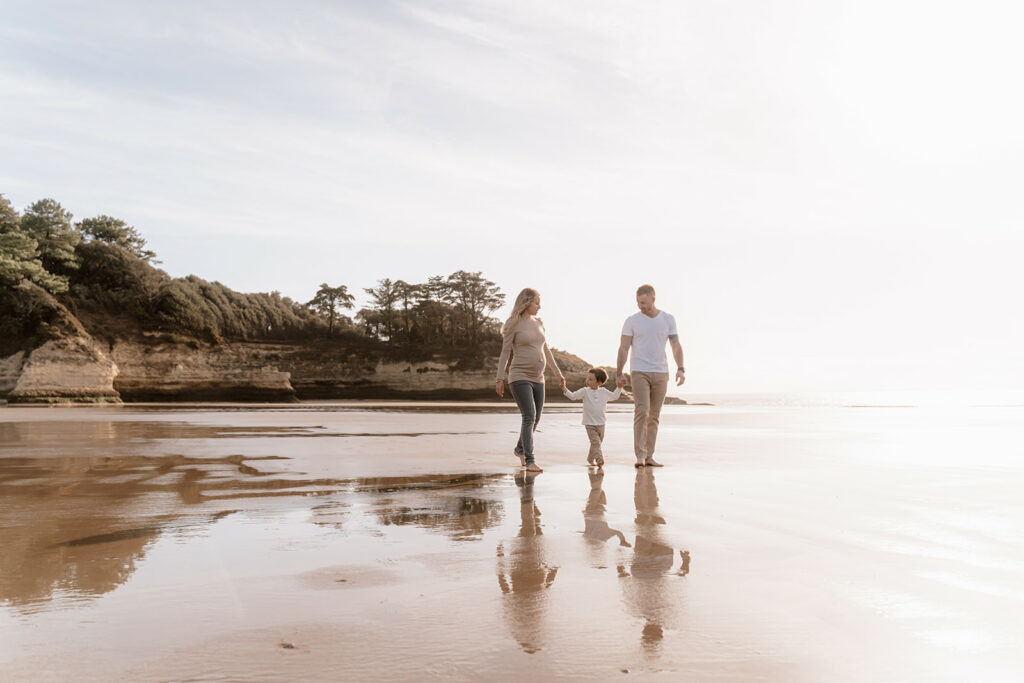 Femme enceinte et sa famille profitant d'une séance photo de grossesse au crépuscule sur la plage de Meschers, capturant la beauté naturelle et la douceur de l'instant.