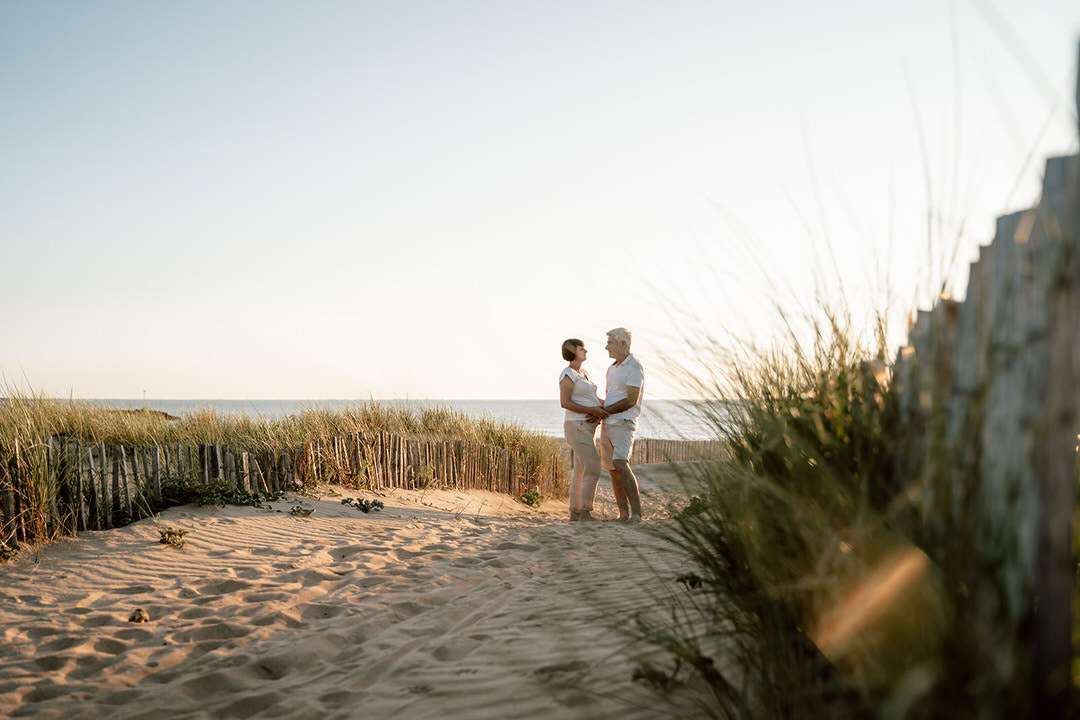 couple de futurs parents se tenant les mains sur le sable