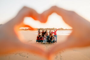 Séance photo EVJF sur l’Île de Ré avec un groupe d’amies souriantes sur la plage, au coucher du soleil, ambiance joyeuse et naturelle